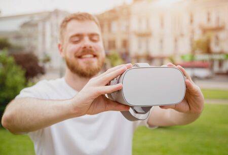 A young man plays a game wearing virtual reality glasses on the street.の写真素材