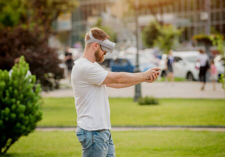 A young man plays a game wearing virtual reality glasses on the street.の写真素材