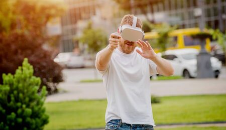 A young man plays a game wearing virtual reality glasses on the street.の写真素材