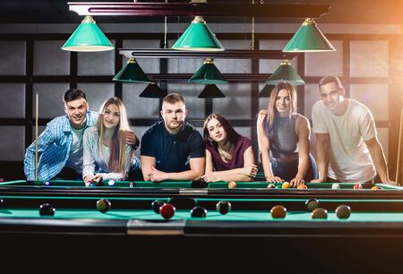 Group of young cheerful friends playing billiards.の写真素材