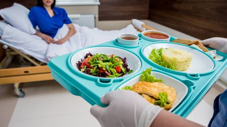 Nurse in medical coat is holding a tray with breakfastの写真素材