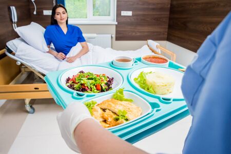 Nurse in medical coat is holding a tray with breakfastの写真素材