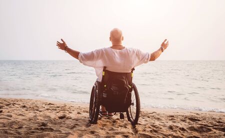 Disabled man in a wheelchair on the beach.の写真素材