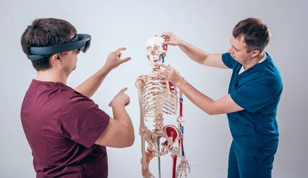 Doctor uses augmented reality goggles and human skeleton for teaching studentの写真素材