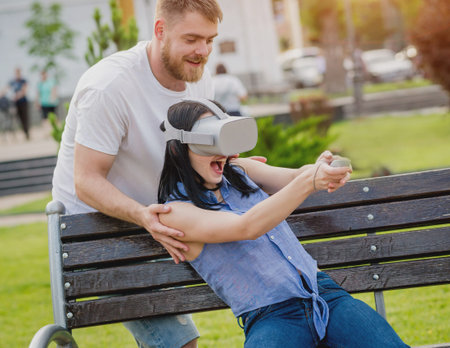 A young couple plays a game using virtual reality glasses on the street.