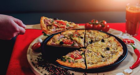 A slice of pizza in his hand. A restaurant. Beautiful backgroundの写真素材