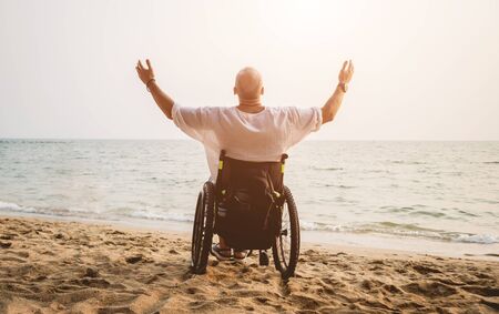 Disabled man in a wheelchair on the beach.の写真素材