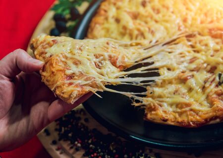 A slice of pizza in his hand. A restaurant. Beautiful backgroundの写真素材