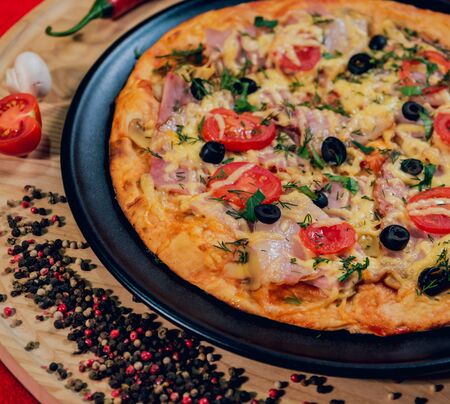 Large hot pizza on the black plate. Restaurant.の写真素材