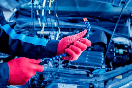 Auto mechanic uses a voltmeter to check the voltage level. Car repair. Service station.の写真素材