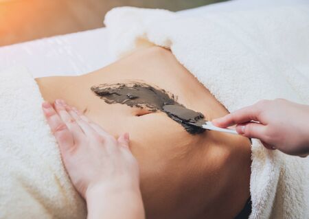 Beautiful woman in spa salon getting mud body massageの写真素材
