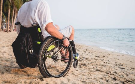 Disabled man in a wheelchair on the beach.の写真素材