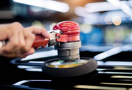 The worker polishes a car with the electric tool.の写真素材