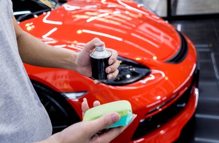 Car service worker applying nano coating on a car detailの写真素材