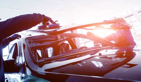 Automobile special workers replacing windscreen or windshield of a car in auto service station garage. Backgroundの写真素材