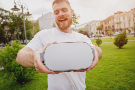 A young man plays a game wearing virtual reality glasses on the street.