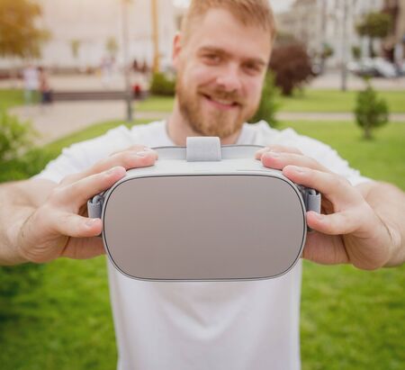 A young man plays a game wearing virtual reality glasses on the street.の写真素材