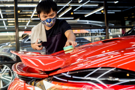 Car service worker applying nano coating on a car detail