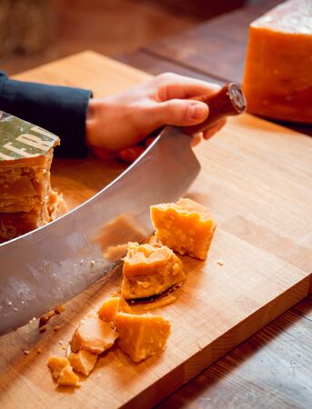 Cut with a knife piece of cheese on a dark table.の写真素材