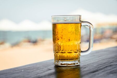 Mug of cold beer with foam on the table.の写真素材