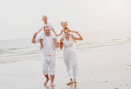 Happy young family on the sunset at the beach.の写真素材