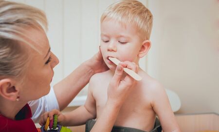 Pediatrician examines a newborn baby with a spatulaの写真素材