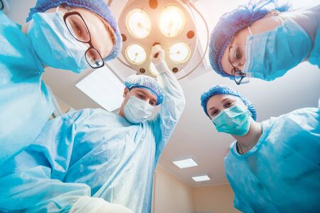 Group of surgeons in operating room with surgery equipment.の写真素材