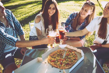 Cheerful friends on picnic in the park. Eating pizzaの写真素材