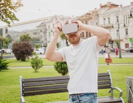 A young man plays a game wearing virtual reality glasses on the street.の写真素材