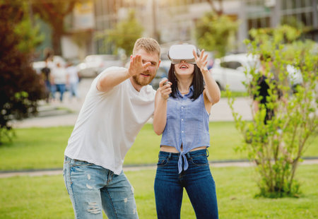 A young couple plays a game using virtual reality glasses on the street.