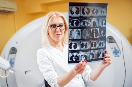 Female radiologist looking at x-ray in the room of computed tomography.