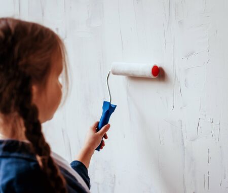 Little girl in a room with a wooden wall. Construction, repair, interior.の写真素材