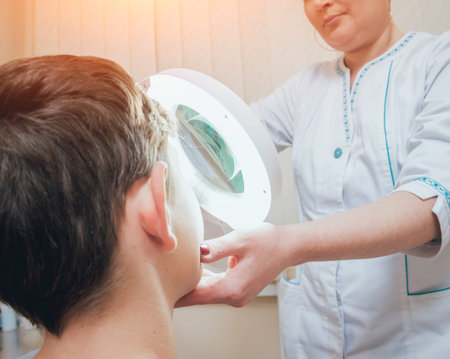 Concentrated dermatologist using medical loupe in the clinic. Medical equipmentの写真素材