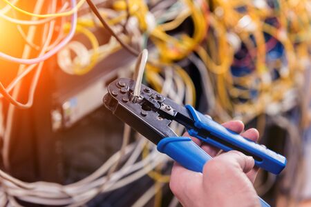 Network engineer working in server room. Connecting network cables to switchesの写真素材