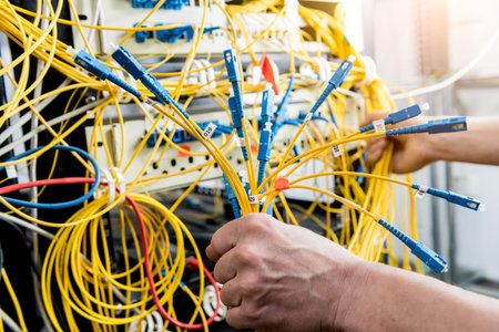 Network engineer working in server room. Connecting network cables to switches