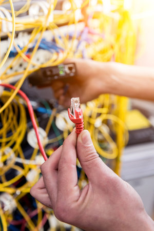 Network engineer working in server room. Connecting network cables to switches