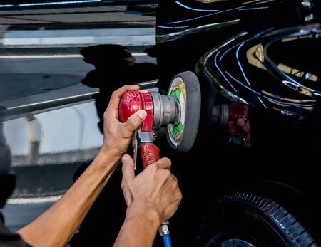 The worker polishes a car with the electric tool.の写真素材