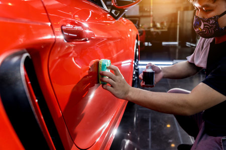 Car service worker applying nano coating on a car detailの写真素材