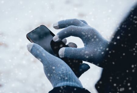 Man using smartphone in winter with gloves for touch screens. Backgoundの写真素材