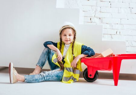 Little girl with wheelbarrow on the white background. Constructionの写真素材