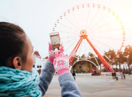 Beautiful girl taking picture of a Ferris wheelの写真素材