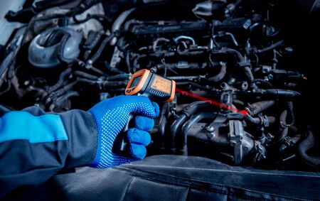 infrared laser thermometer in hand. Motor temperature measurement in the car serviceの写真素材