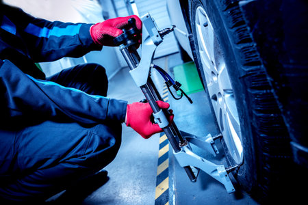 Car mechanic installing sensor during suspension adjustment. Wheel alignment work at repair service...
