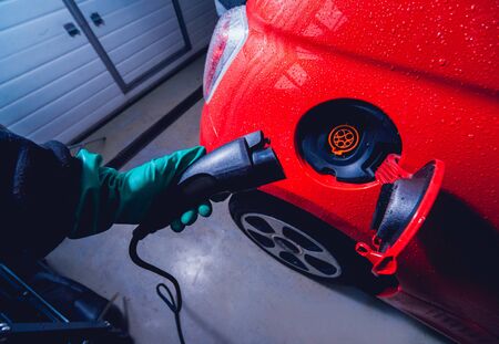 Charging an electric vehicle in the car service. Future of the automobile. Red colorsの写真素材