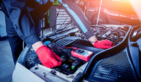 Auto mechanic uses a voltmeter to check the voltage level. Car repair. Service station.の写真素材