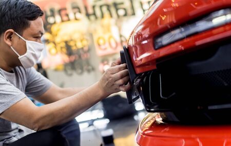 Technician changing car plate number in service center. Light backgroundの写真素材