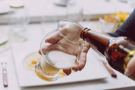 Glass of lager beer in the hands. Restaurantの写真素材