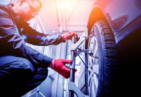 Car mechanic installing sensor during suspension adjustment.の写真素材
