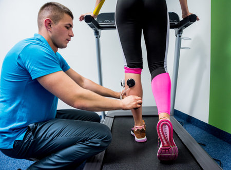 Physical therapist install electrostimulator on the muscles of the legs