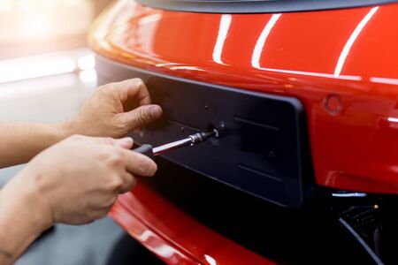 Technician changing car plate number in service center. Light backgroundの写真素材